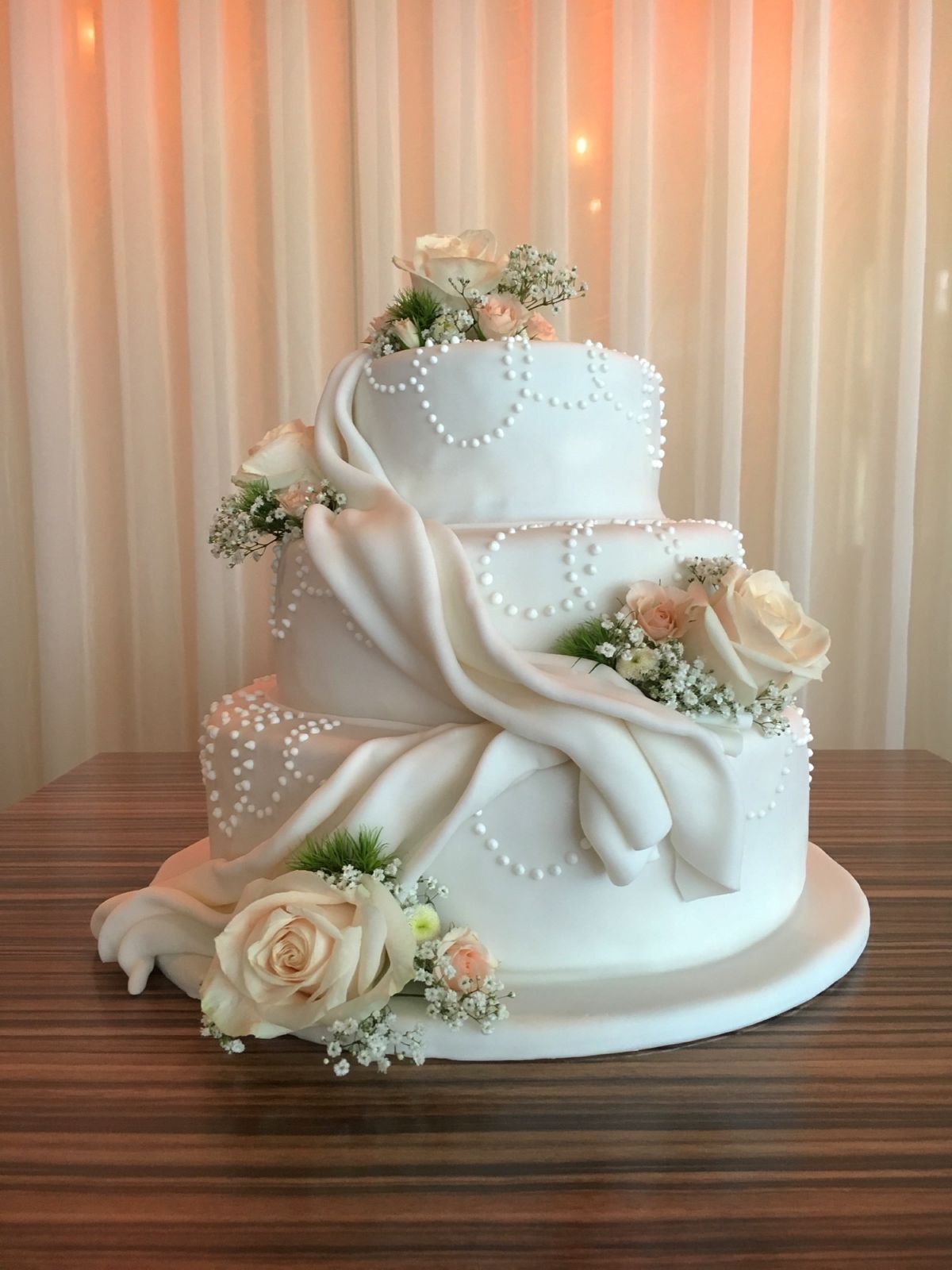Dreistöckige Hochzeitstorte mit Tuchdraping und frischen Pfirsich-Rosen