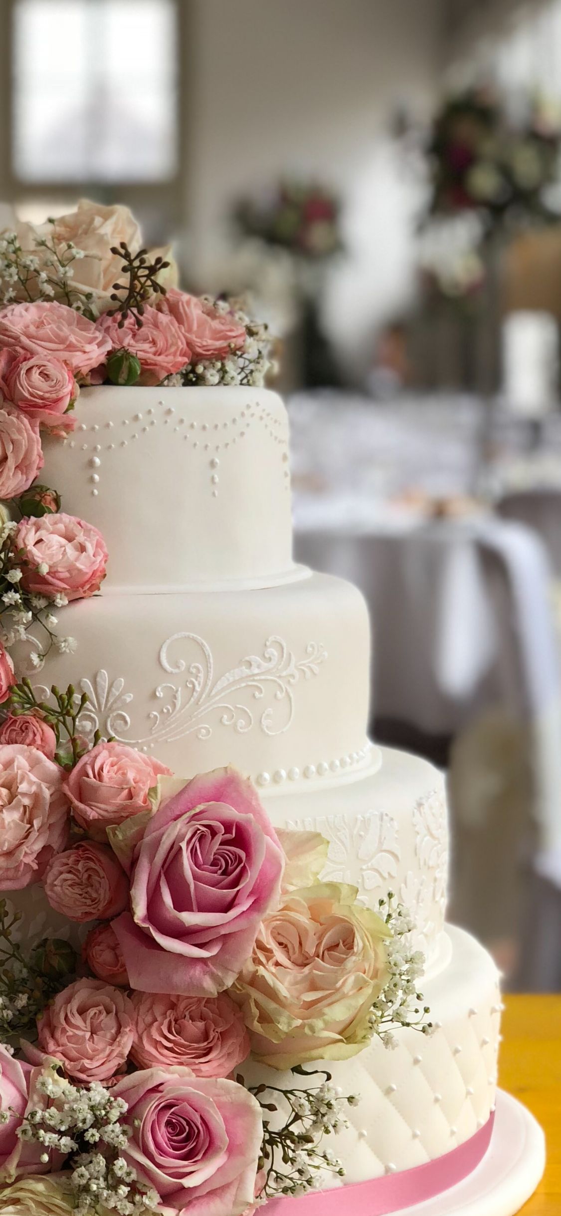 Dreistöckige Hochzeitstorte mit Perlenband und rosa Rosenkaskade