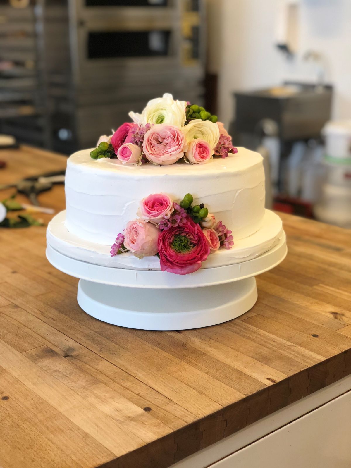 Zweistöckige Hochzeitstorte in Weiß, Rosa und Creme mit frischen Rosen
