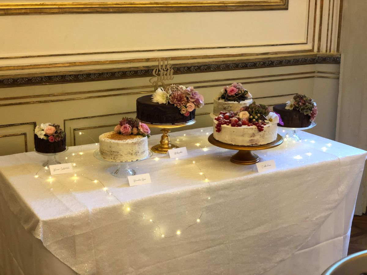 Hochzeitstorten-Auswahl auf dekoriertem Tisch mit Fadenlicht und beschrifteten Kärtchen