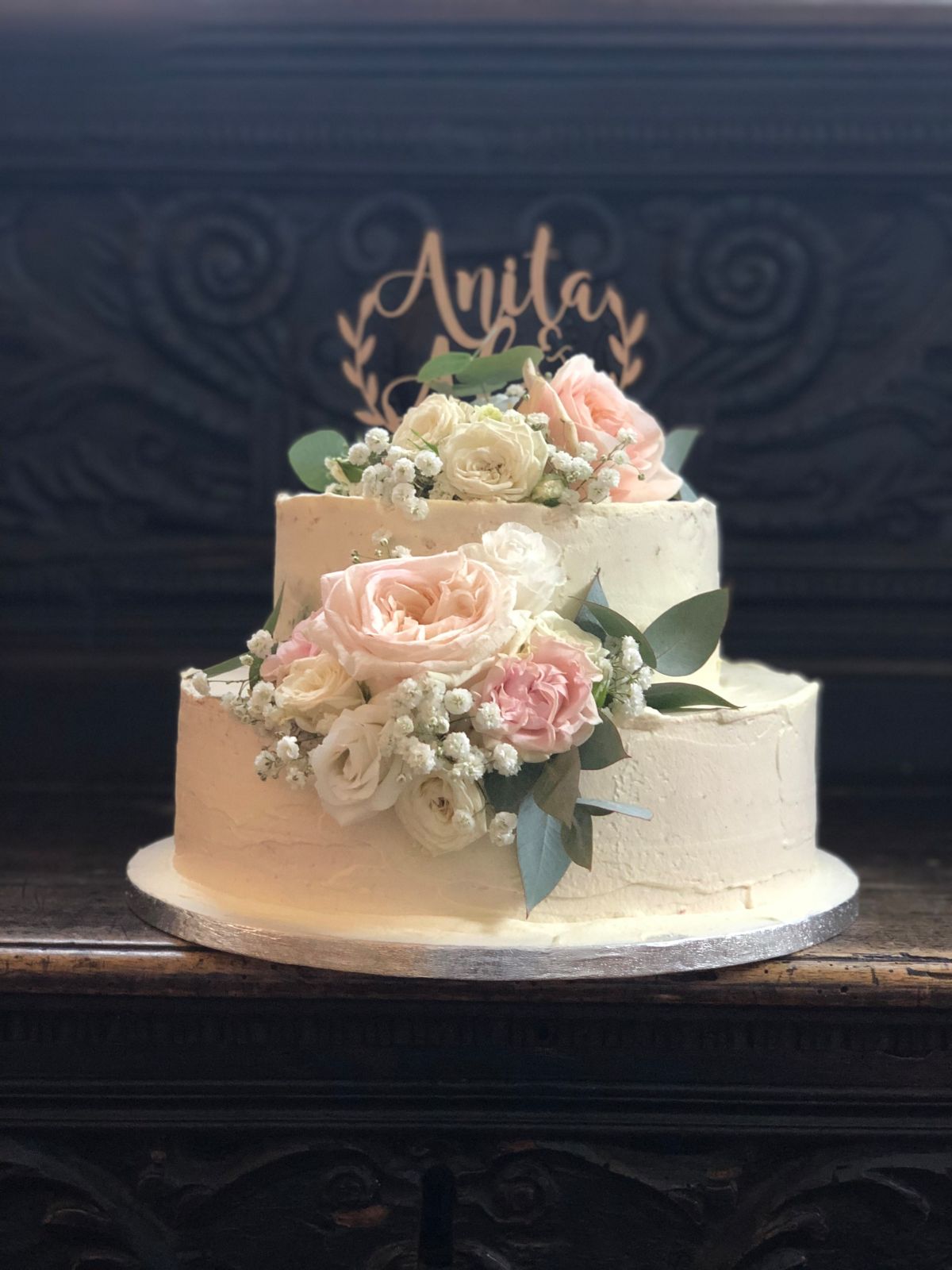 Zweistöckige Hochzeitstorte mit goldenem Namens-Topper und Mauve-Rosenkaskade