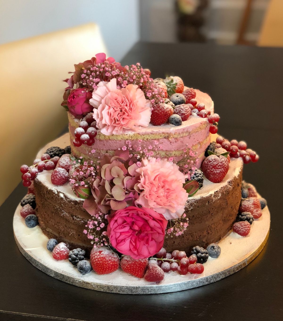 Zweistöckige Hochzeitstorte mit Mauve-Peonien, rosa Nelken und frischen Beeren