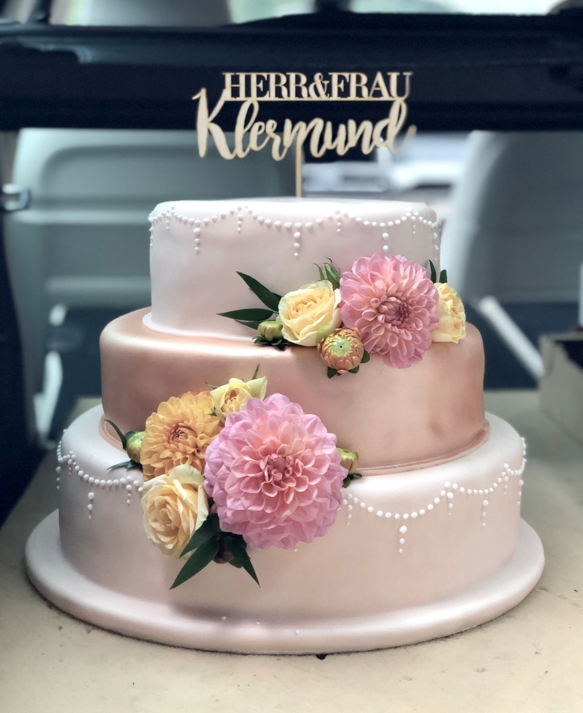 Dreistöckige Ombré-Hochzeitstorte von Weiß zu Pink mit Pfingstrosen, gelben Nelken und Namens-Topper