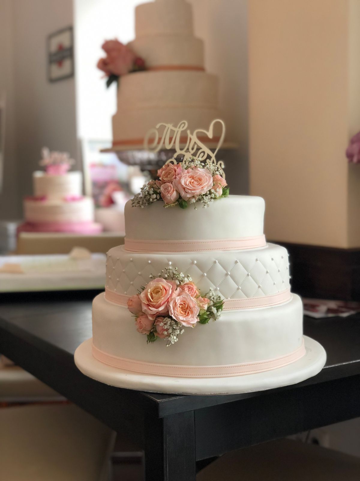 Vierstöckige Hochzeitstorte mit gesteppter Fondanttextur, Rosenblüten und 'until forever'-Topper