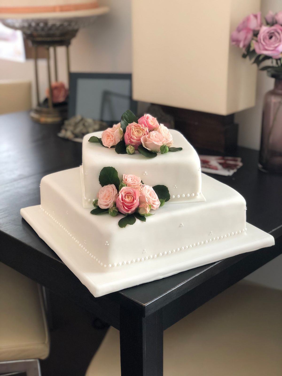Zweistöckige quadratische Hochzeitstorte mit pfirsich-rosa Rosen und feinen Perlendetails