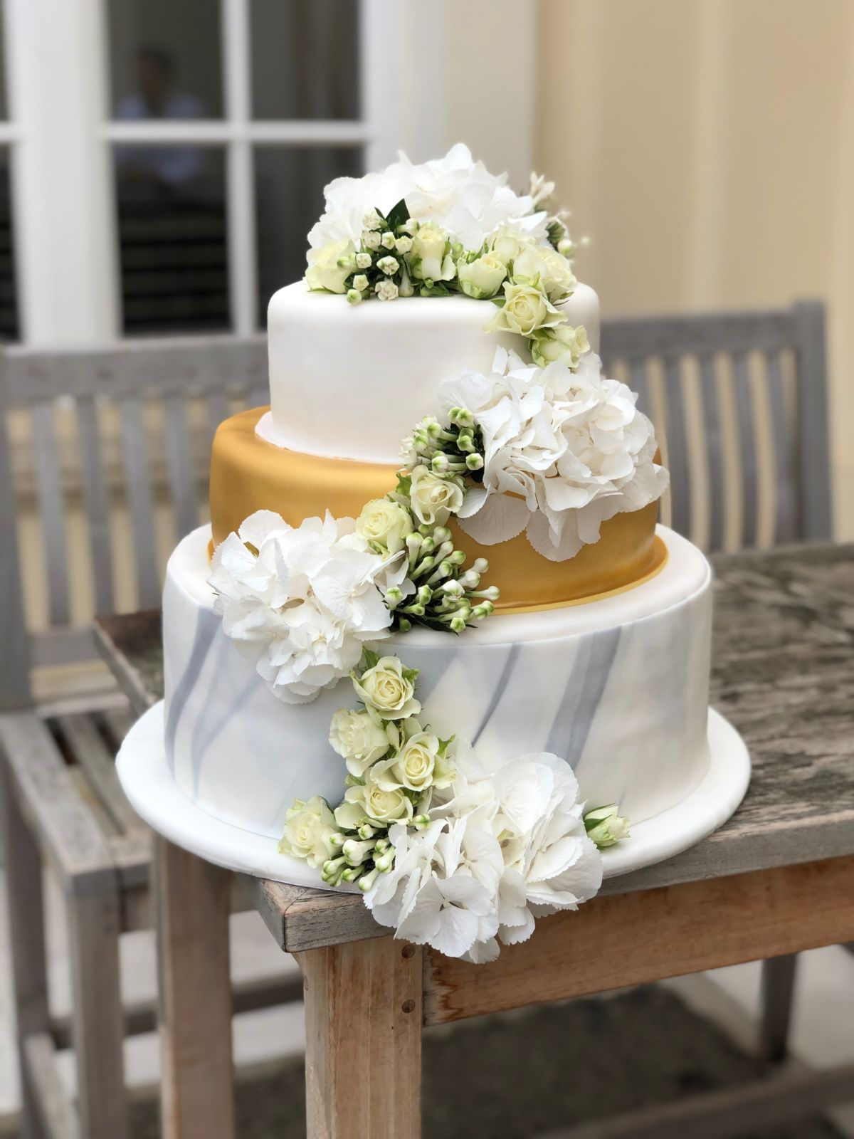 Dreistöckige Hochzeitstorte mit Goldband-Akzent und kaskadierenden gelben Rosen
