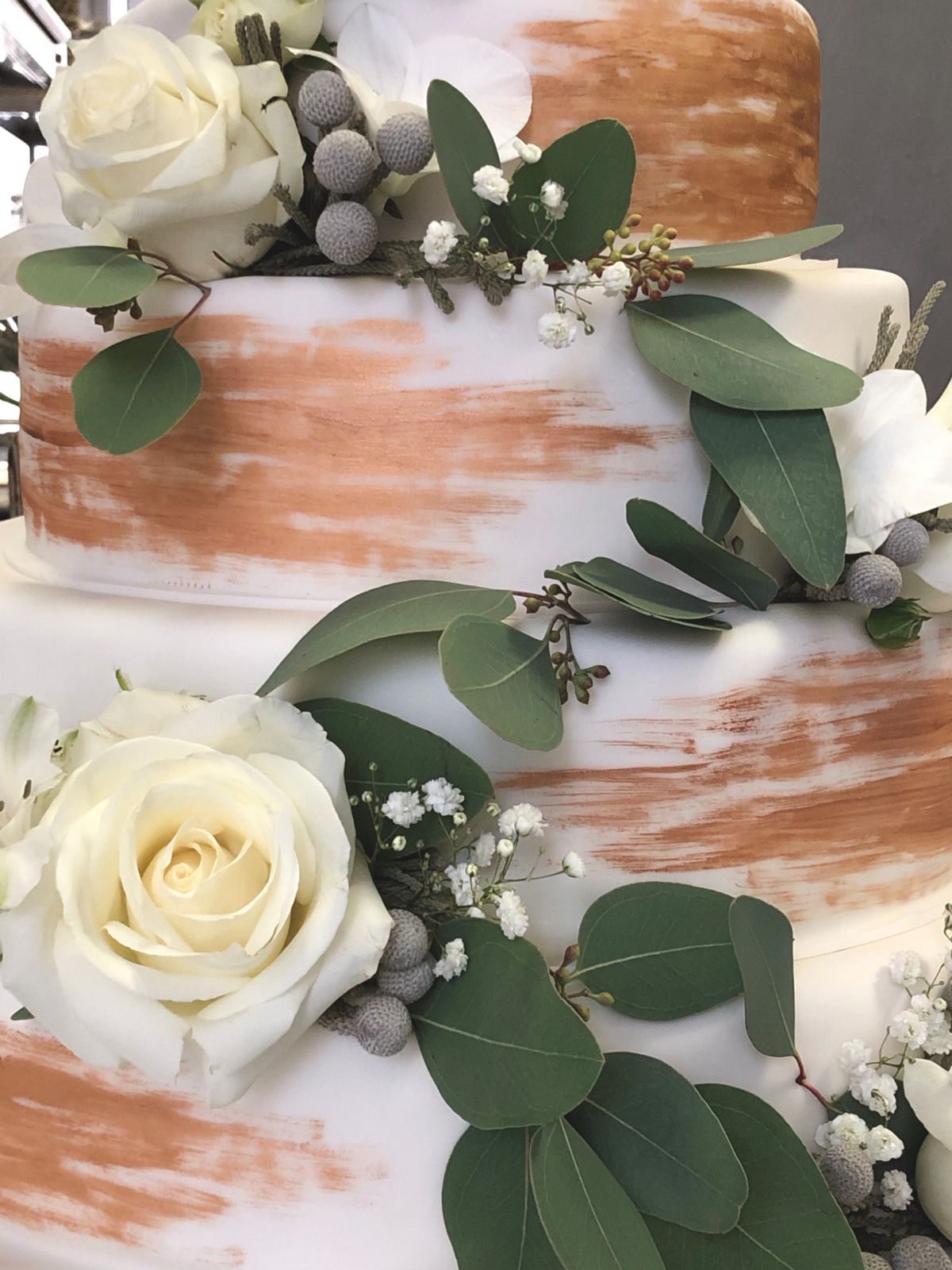 Zweistöckige Aquarell-Hochzeitstorte in Rosegold mit weißen Rosen, Eukalyptus und Brunia-Beeren