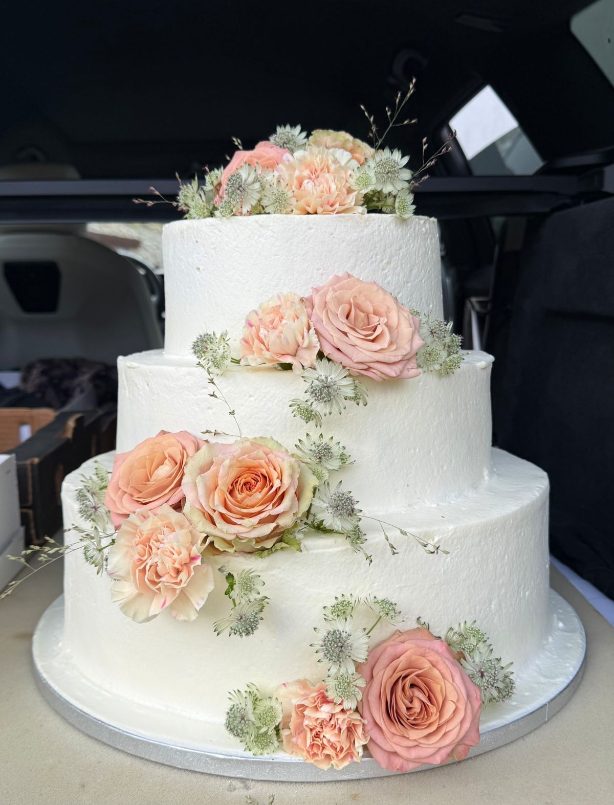 Dreistöckige Hochzeitstorte in Weiß mit Pfirsich-Rosen, Nelken und Sterndolden