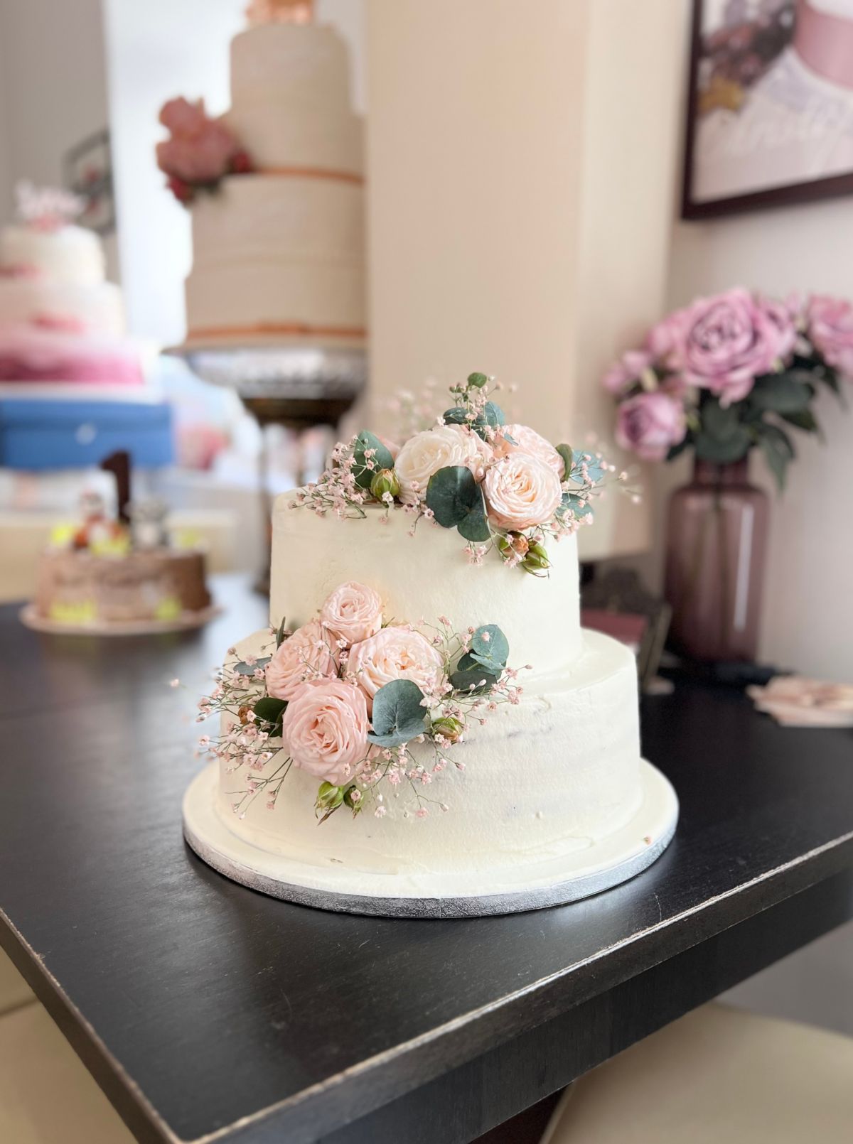 Zweistöckige Hochzeitstorte in Weiß mit zartrosa Rosen und Schleierkraut