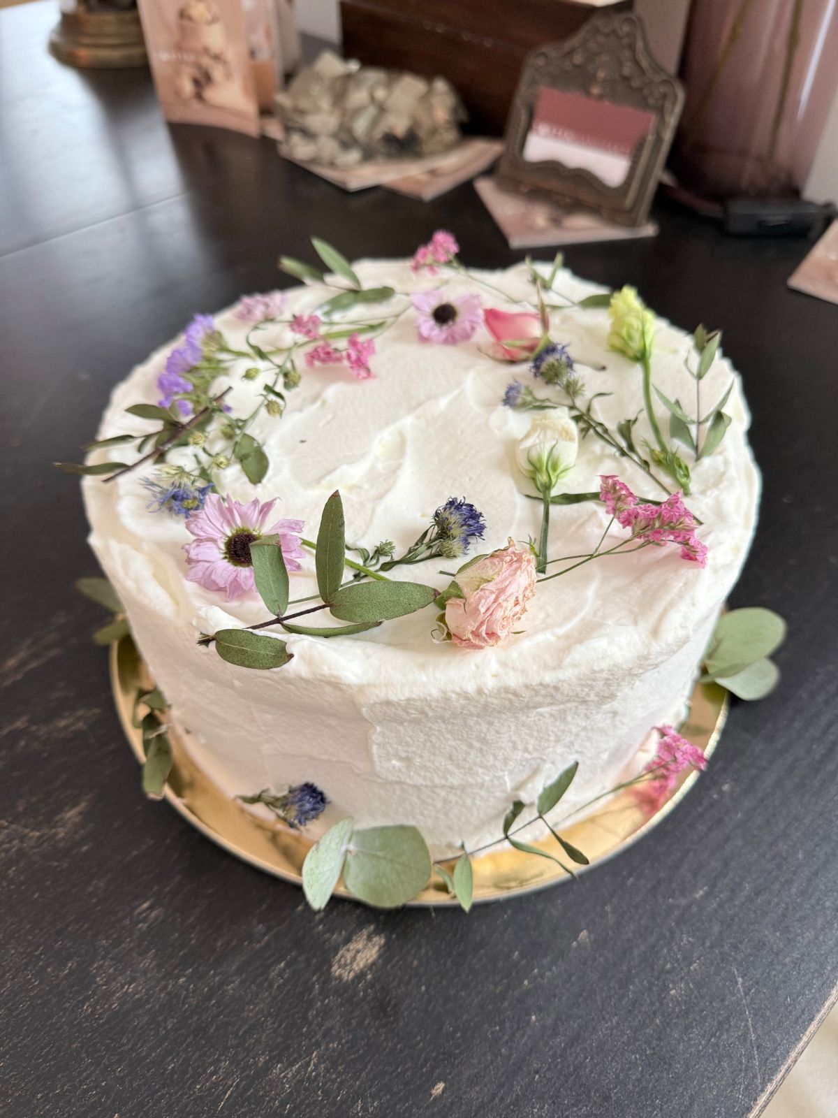 Einstöckige Torte in Weiß mit frischen Wiesenblumen und Eukalyptus