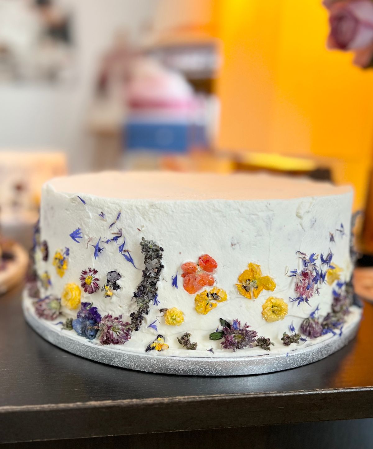 Einstöckige Torte in Weiß mit gepressten essbaren Blüten rundum