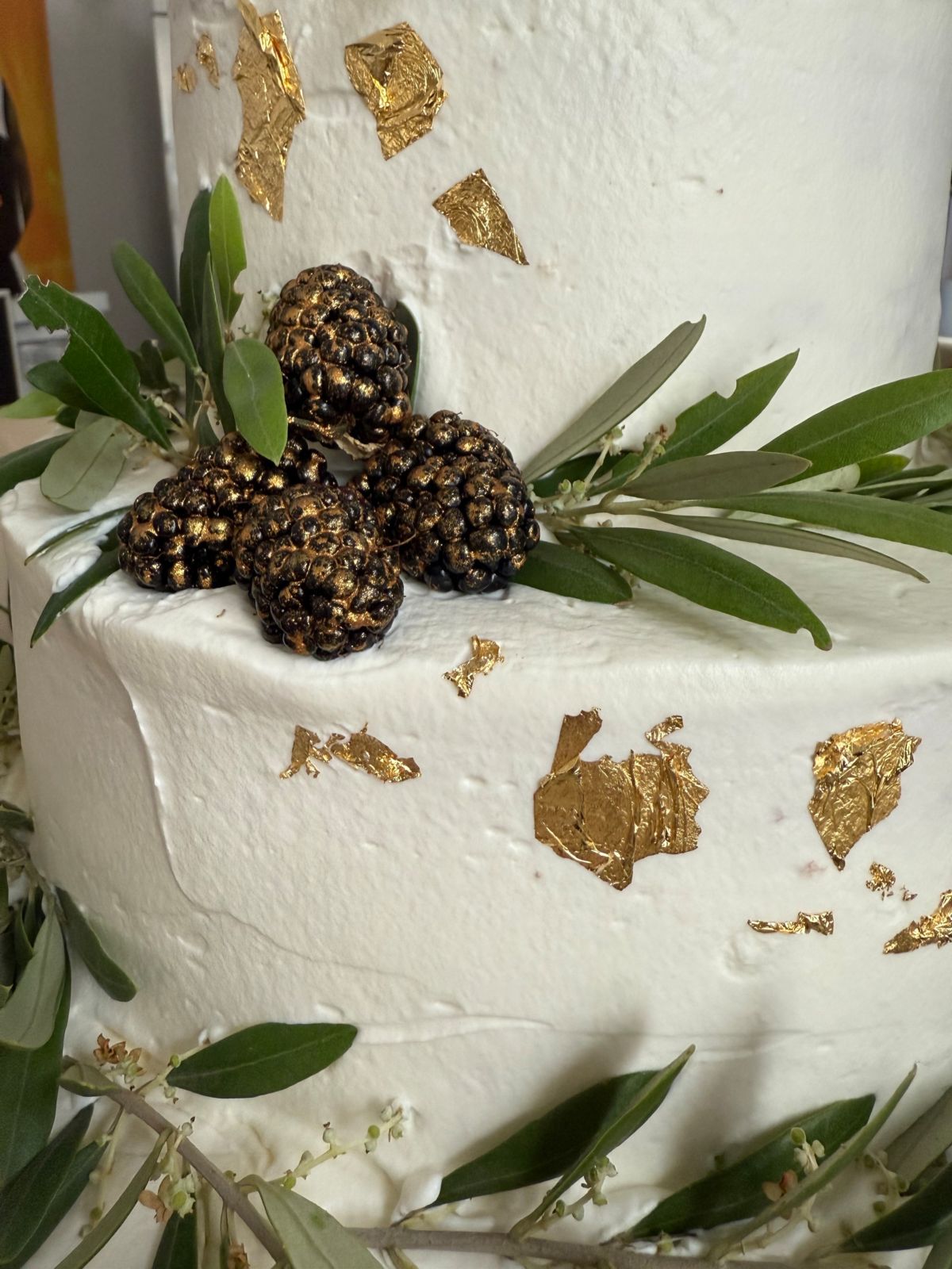 Detail einer Hochzeitstorte mit Blattgold, vergoldeten Brombeeren und Olivenzweigen