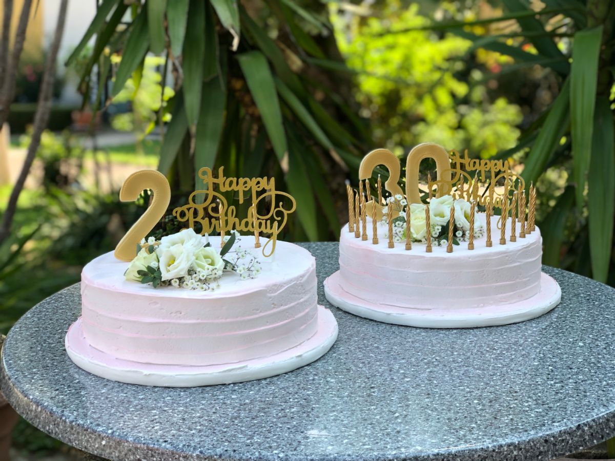 Zwei kleine weiße Geburtstagstorten im Garten zum 2. und zum 60. Geburtstag
