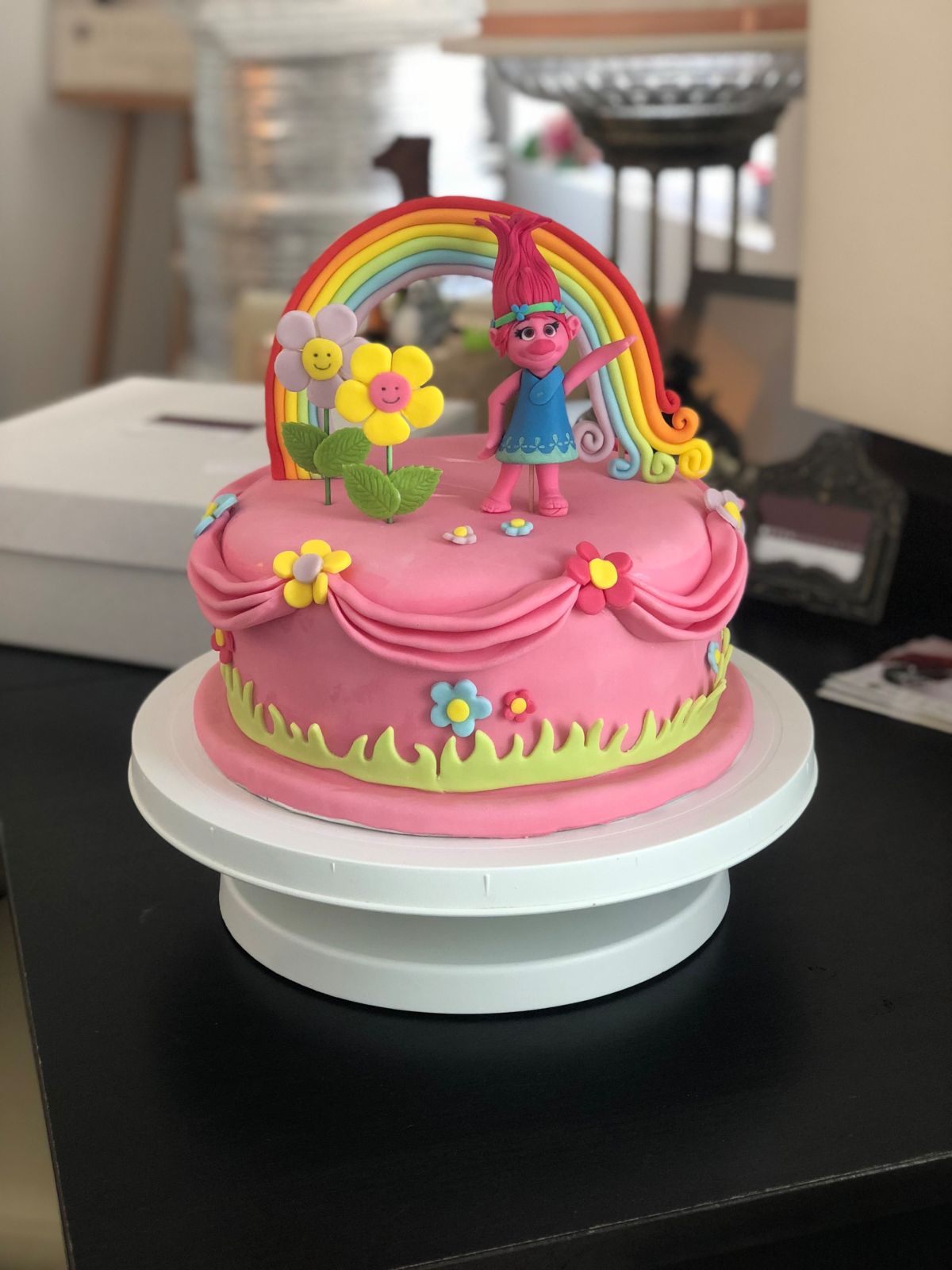 Kindergeburtstagstorte in Rosa mit Trolls-Figur, Regenbogen, Blumen und grünem Grasrand