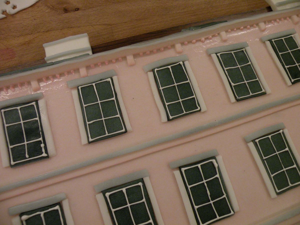 Nahaufnahme rosa Hausfassade mit Fensterdetails und horizontalen Strukturlinien