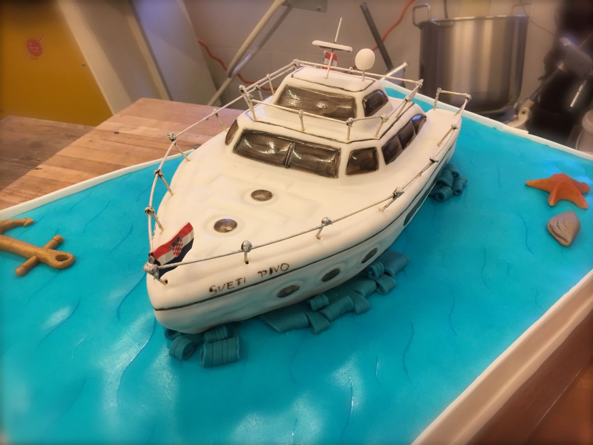 Motorjacht-Motivtorte mit mehreren Decks auf türkisem Fondant-Meer