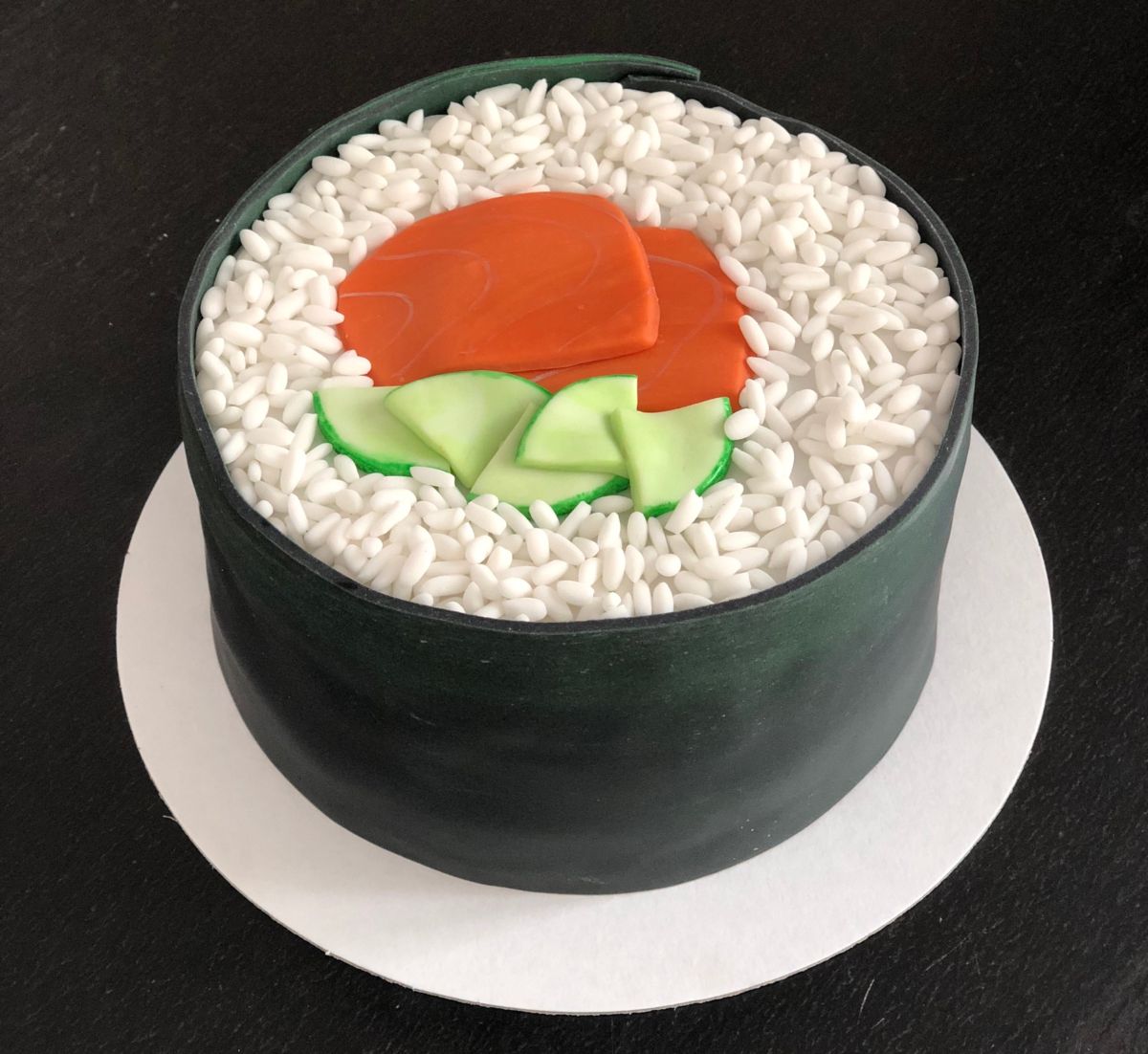 Rosenmotiv-Torte mit roter Blüte und grünem Blattwerk auf Platte