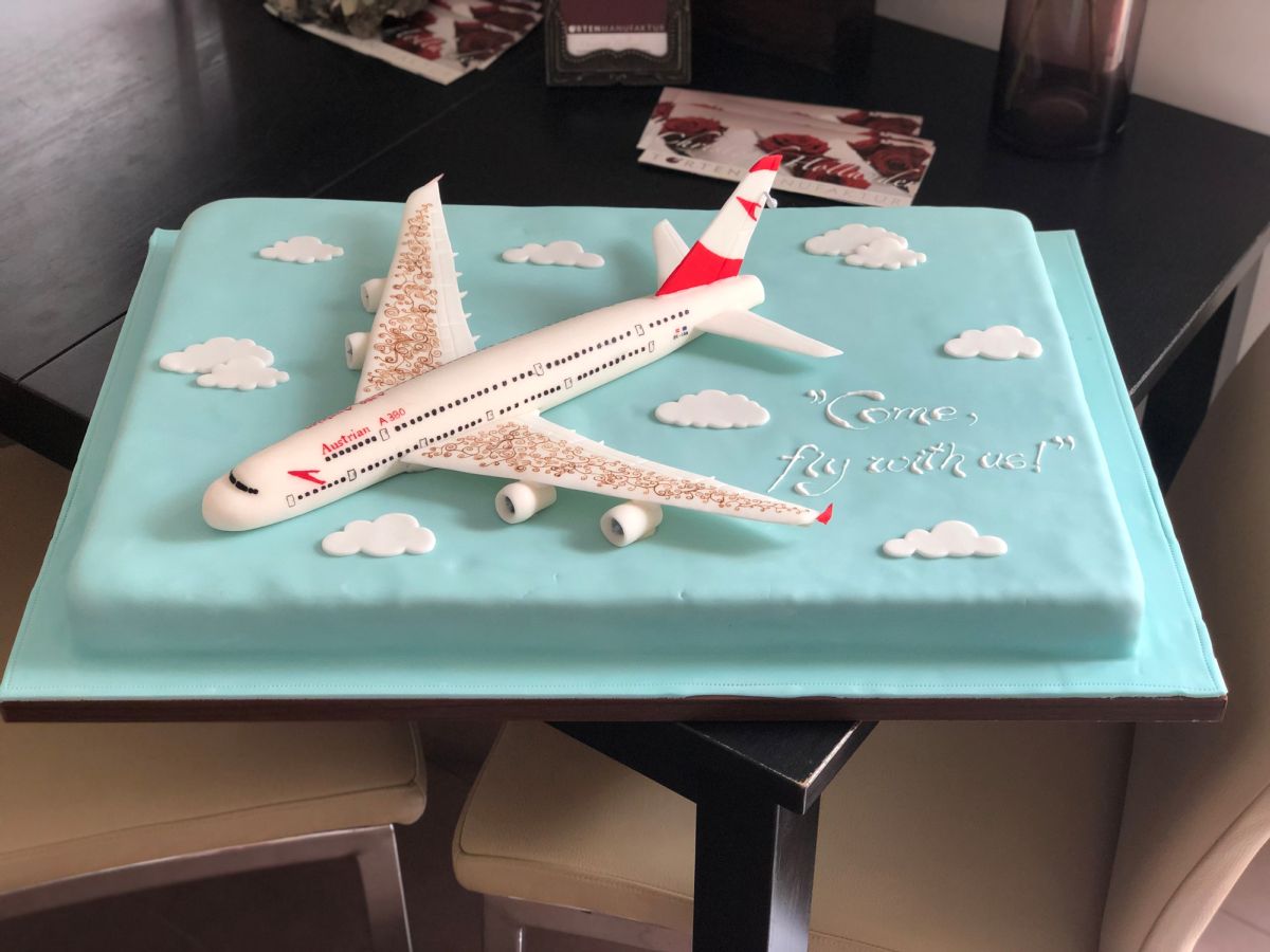 Reise-Torte mit Passagierflugzeug und Wolkenmotiv auf Himmelblau