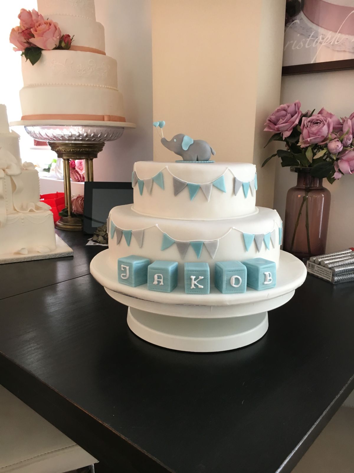 Zweistöckige Tauftorte mit rosa Elefant und Wimpelgirlande
