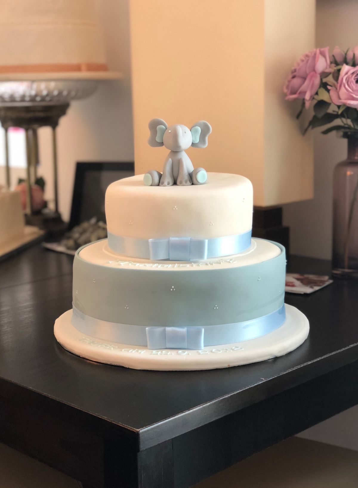 Dreistöckige weiße Tauftorte mit Elefantenfigur und Schleife