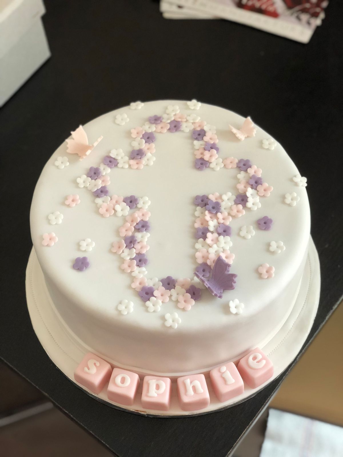 Runde Tauftorte mit Kreuz aus Zuckerblüten in Weiß, Rosa und Violett