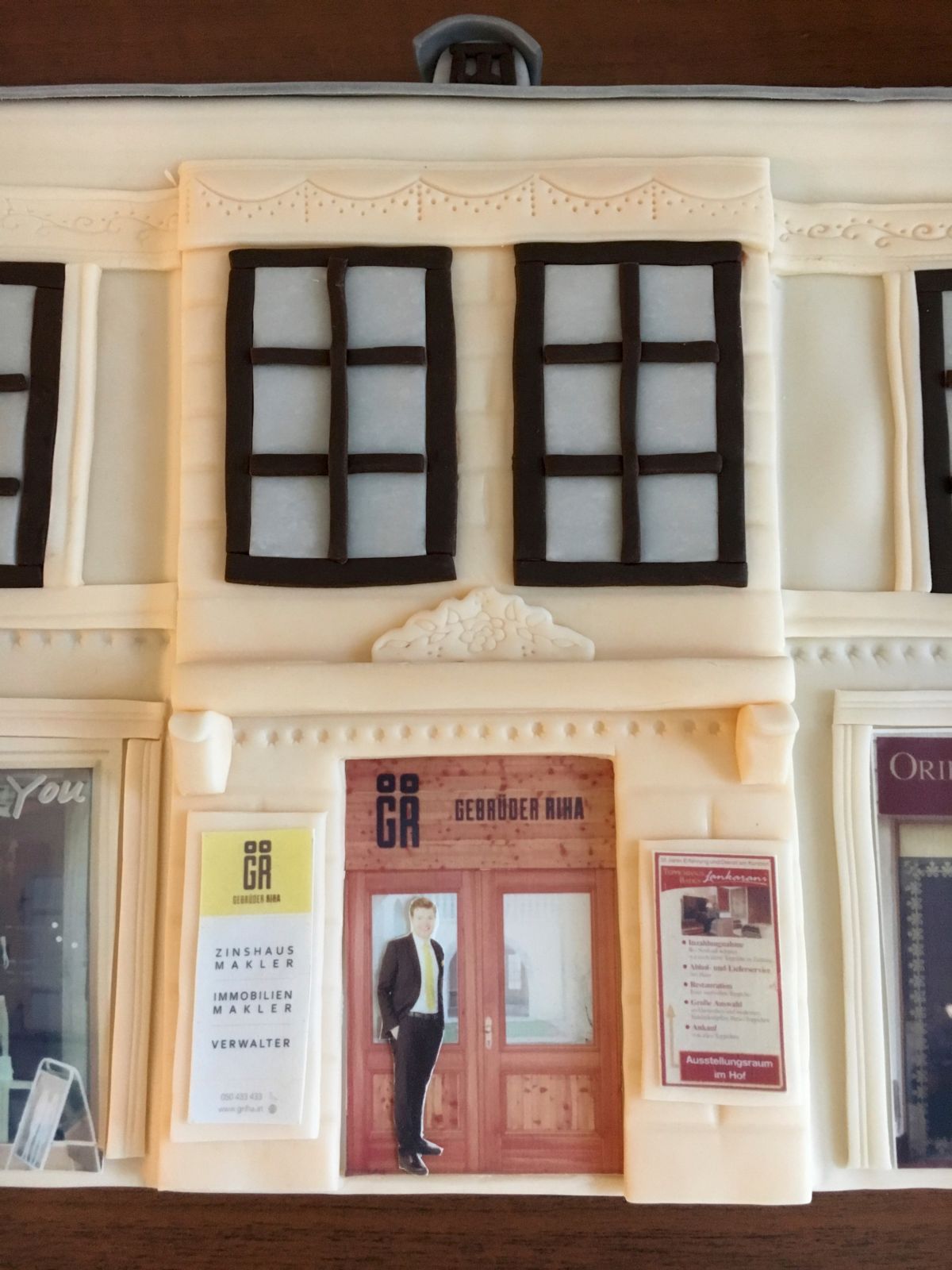Nahaufnahme einer Shopfassade mit schwarzgerahmten Fenstern, roter Tür und Schaufenster-Dekorationen