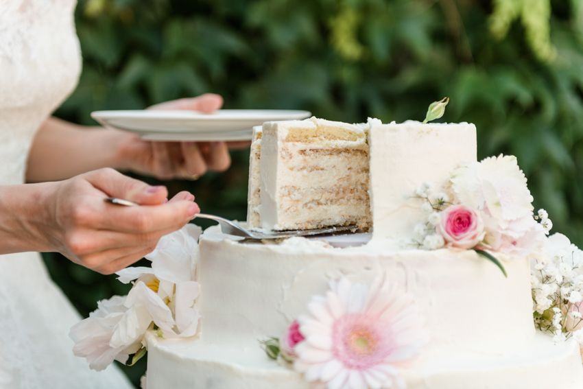 Naked cake being served at a wedding reception, two-tier white cake