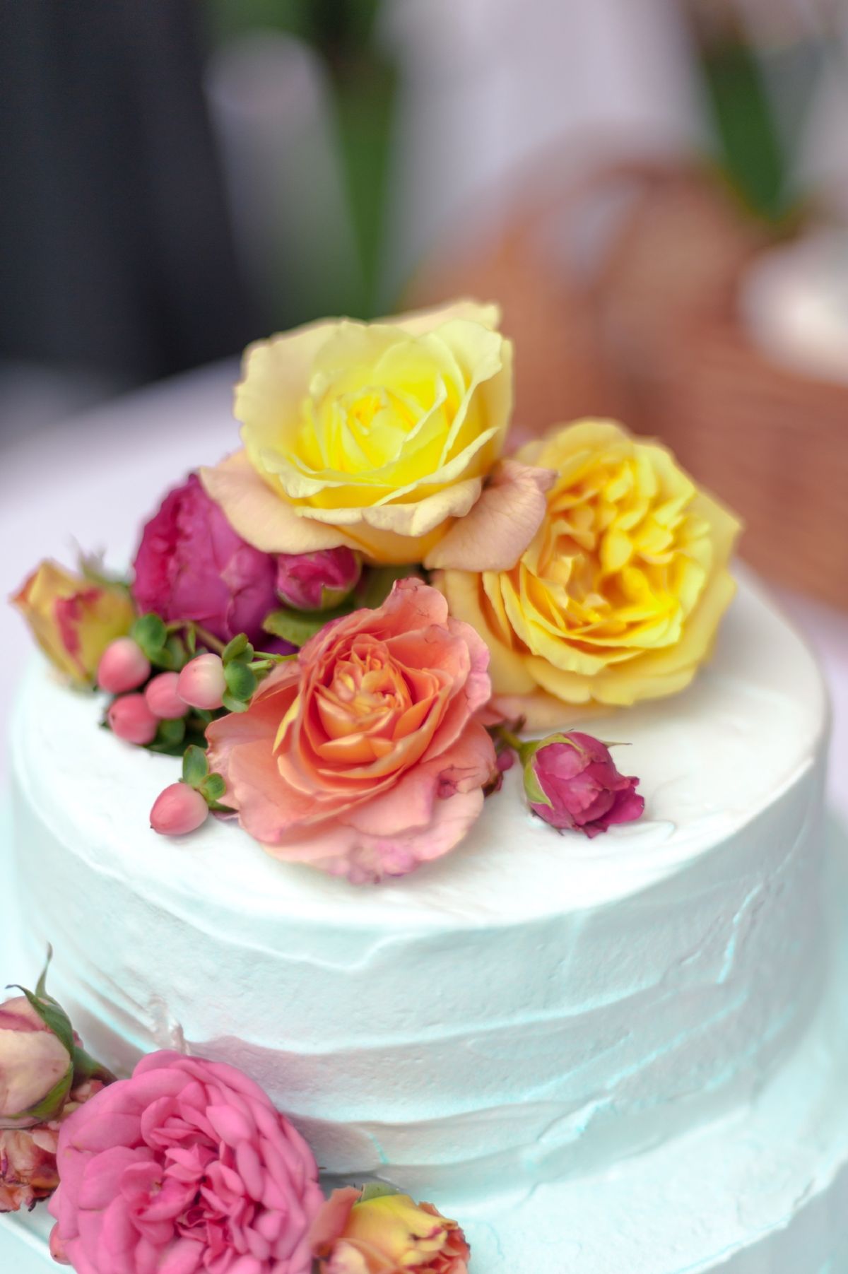 Two-tier pale turquoise wedding cake with yellow, pink and orange fresh roses