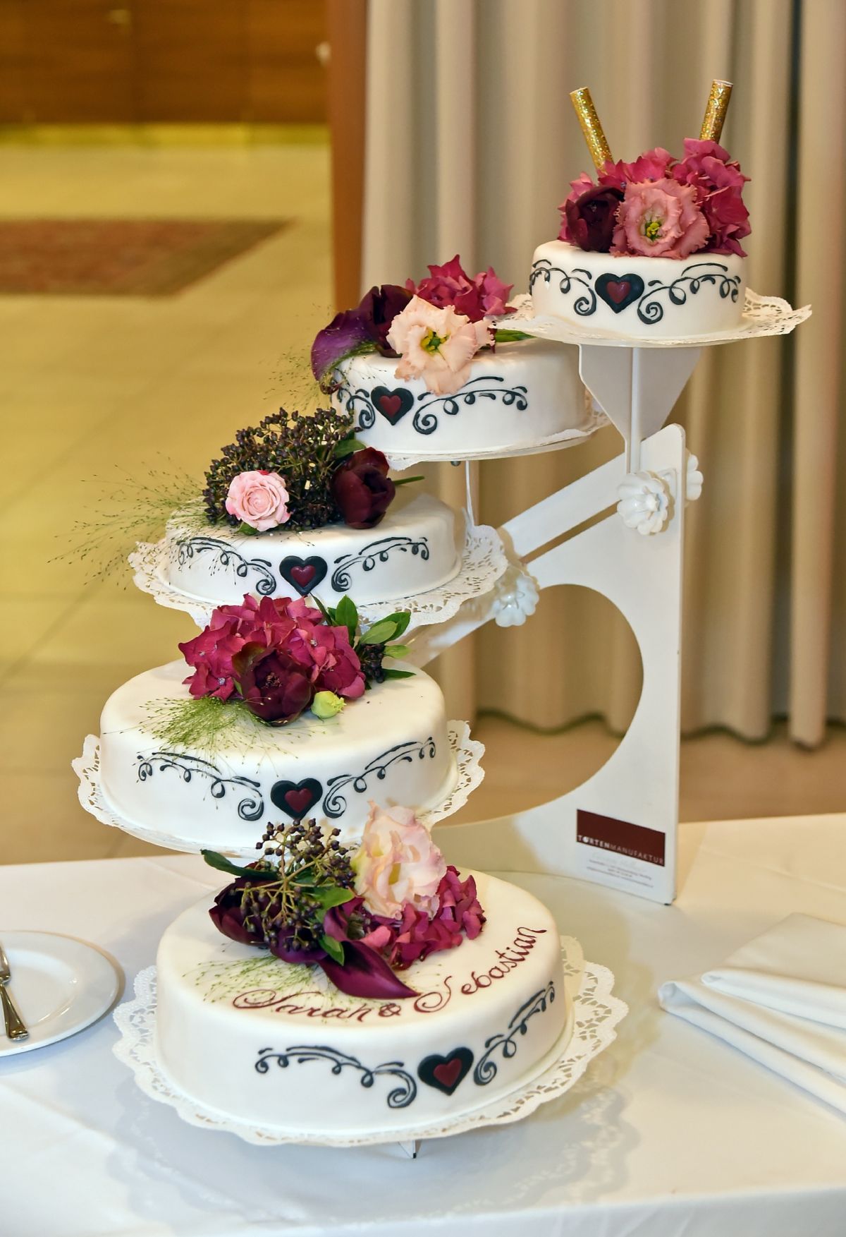 Heart-shaped wedding cake with hand-painted hearts and pink and burgundy roses
