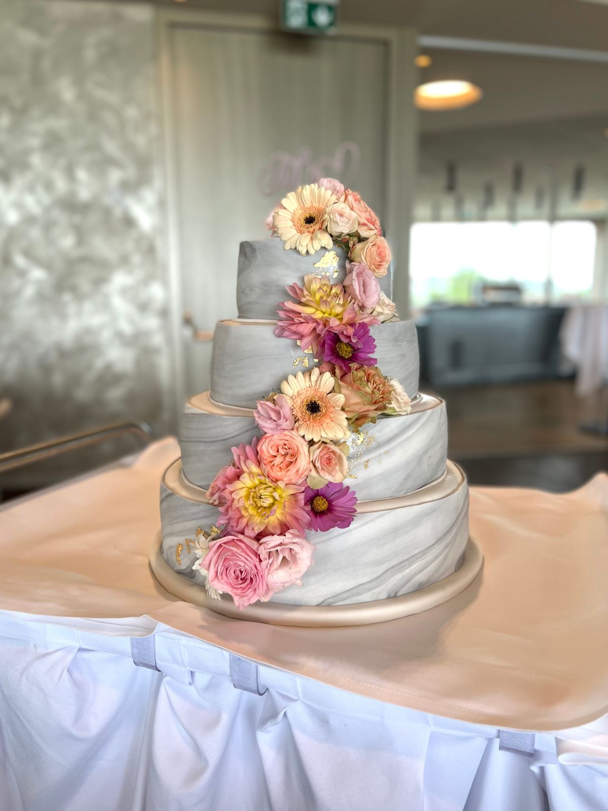 Four-tier marbled wedding cake with a cascade of gerberas and roses