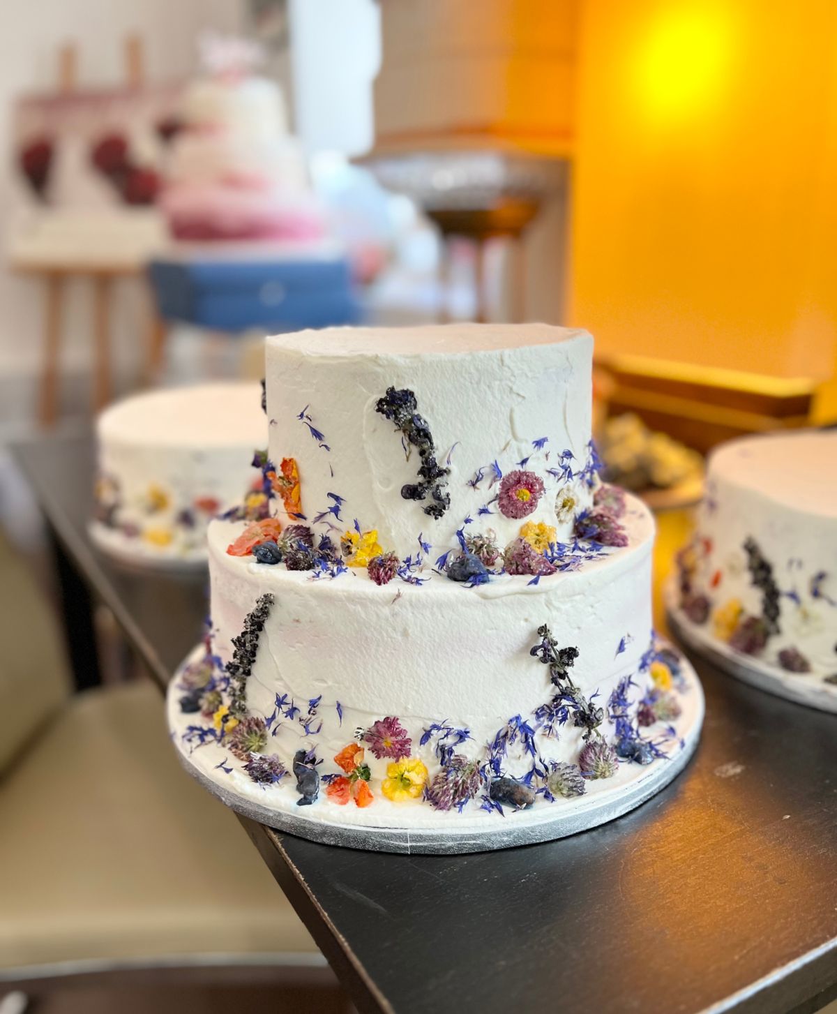 Two-tier wedding cake with pressed edible flowers in violet and yellow