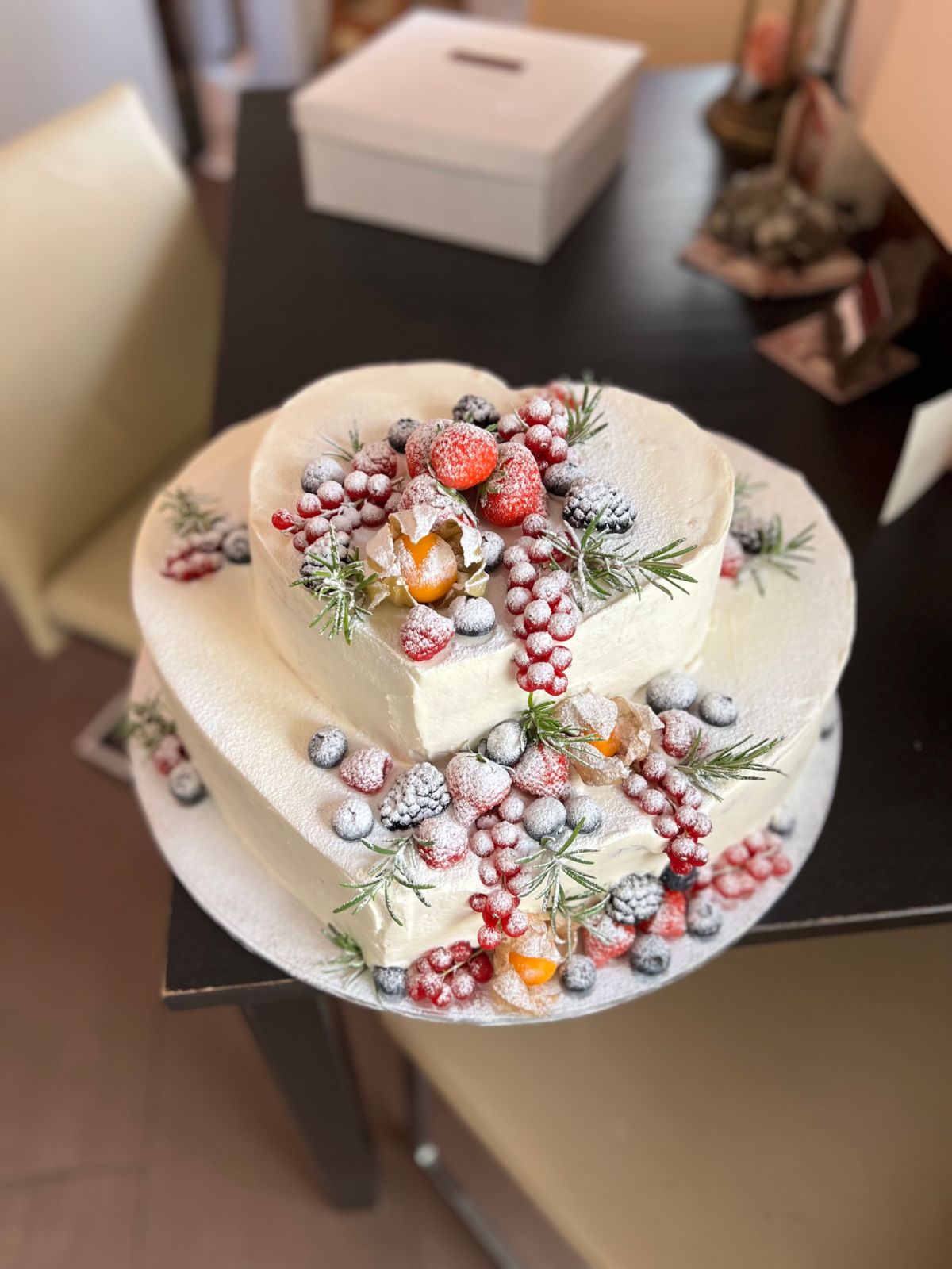 Two-tier heart-shaped cake with sugared berries, physalis and rosemary