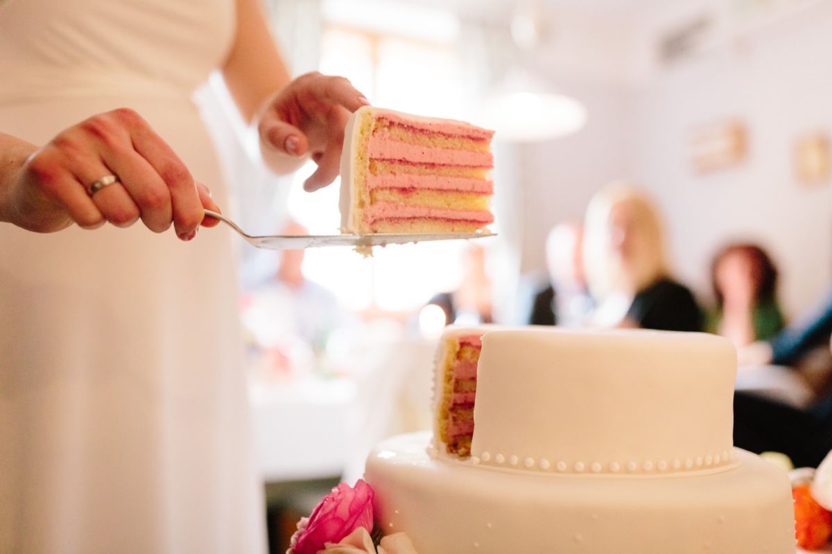 Wedding cake being cut – two-tier white cake with pearl decoration
