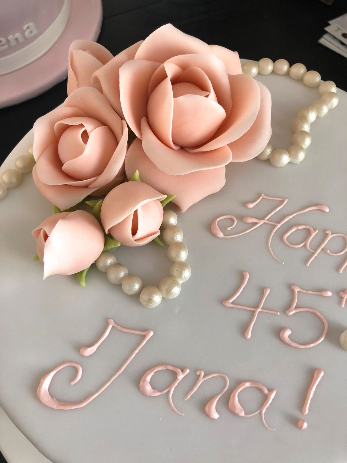 Cake with grey fondant decorated with pink sugar roses and pearl swag