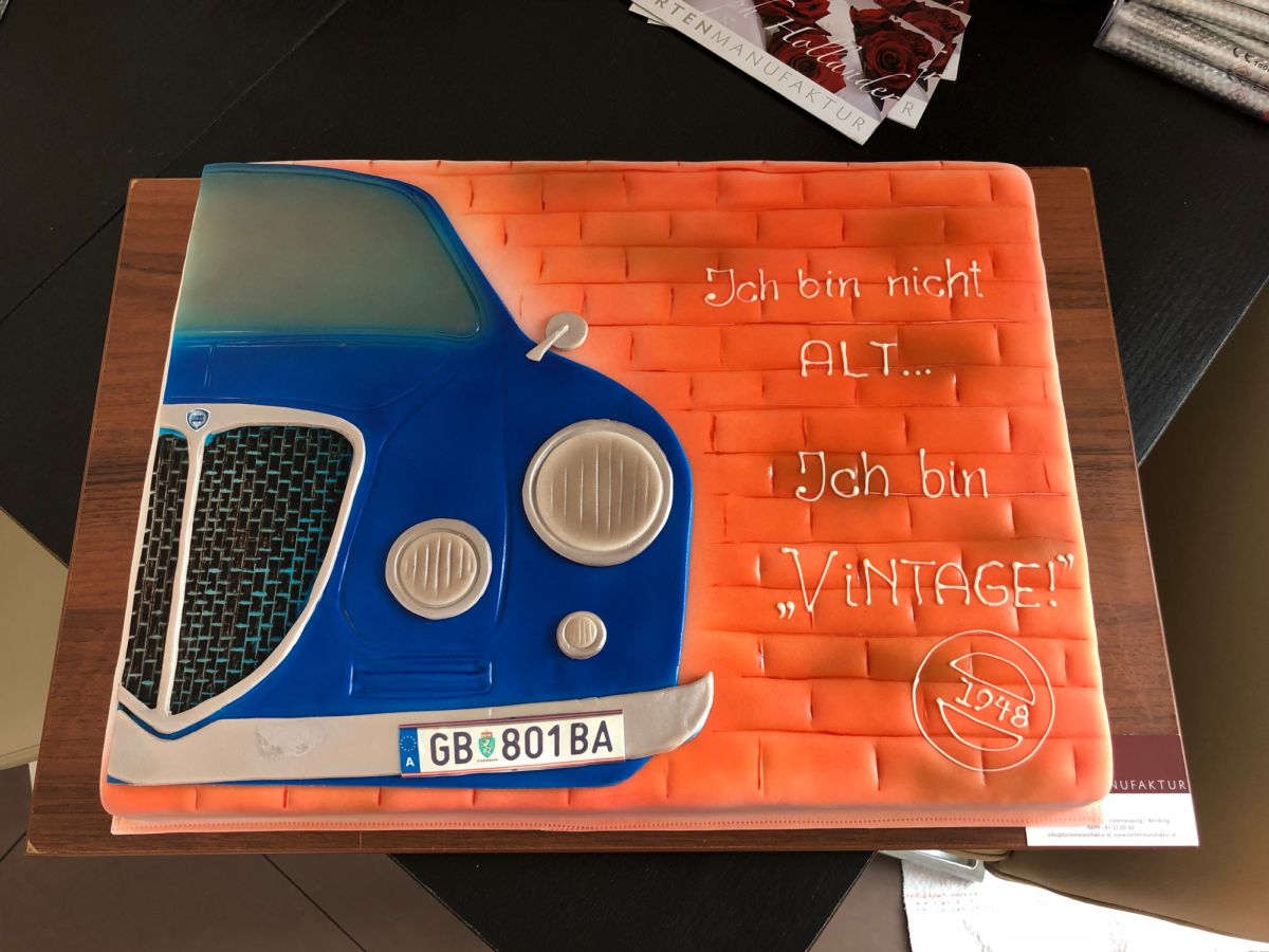 Birthday cake with a blue 1978 vintage car against brick backdrop