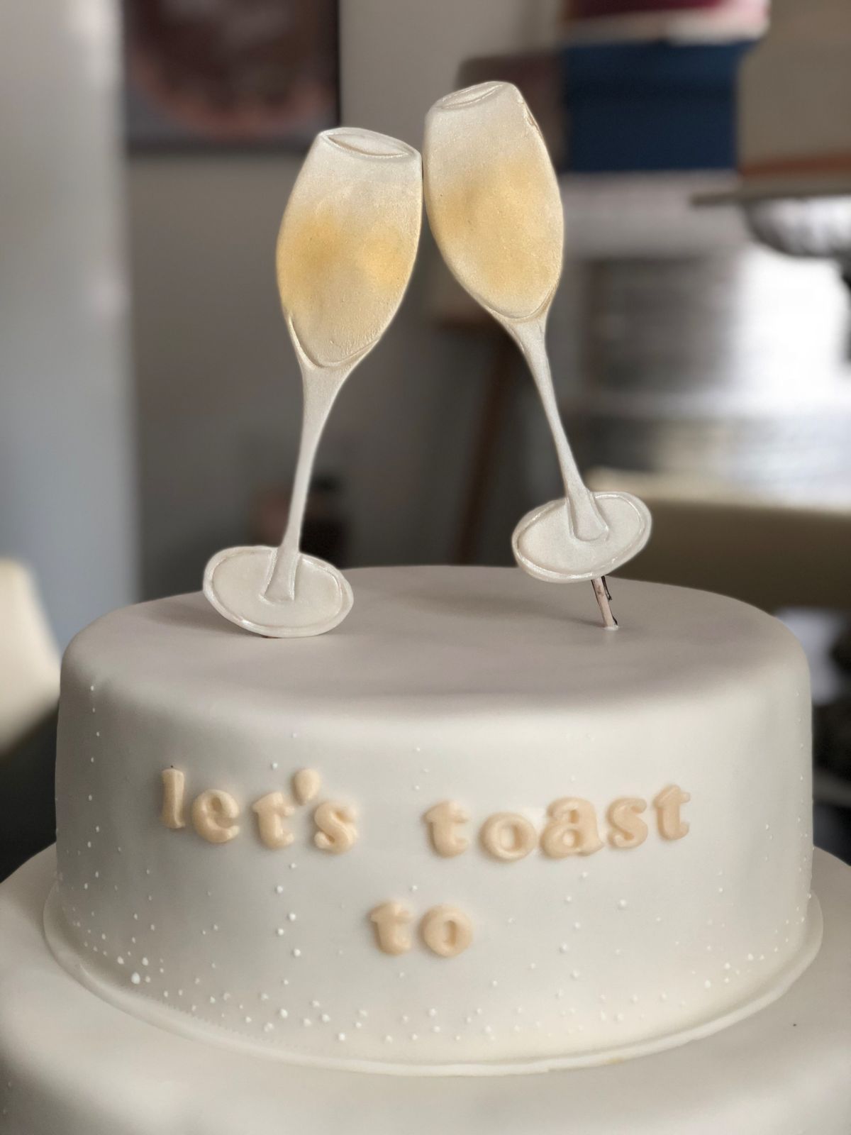 White birthday cake decorated with two champagne flute toppers