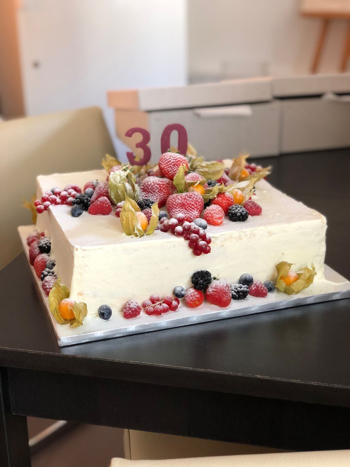 Rectangular cake with number 30, topped with fresh berries and physalis flowers