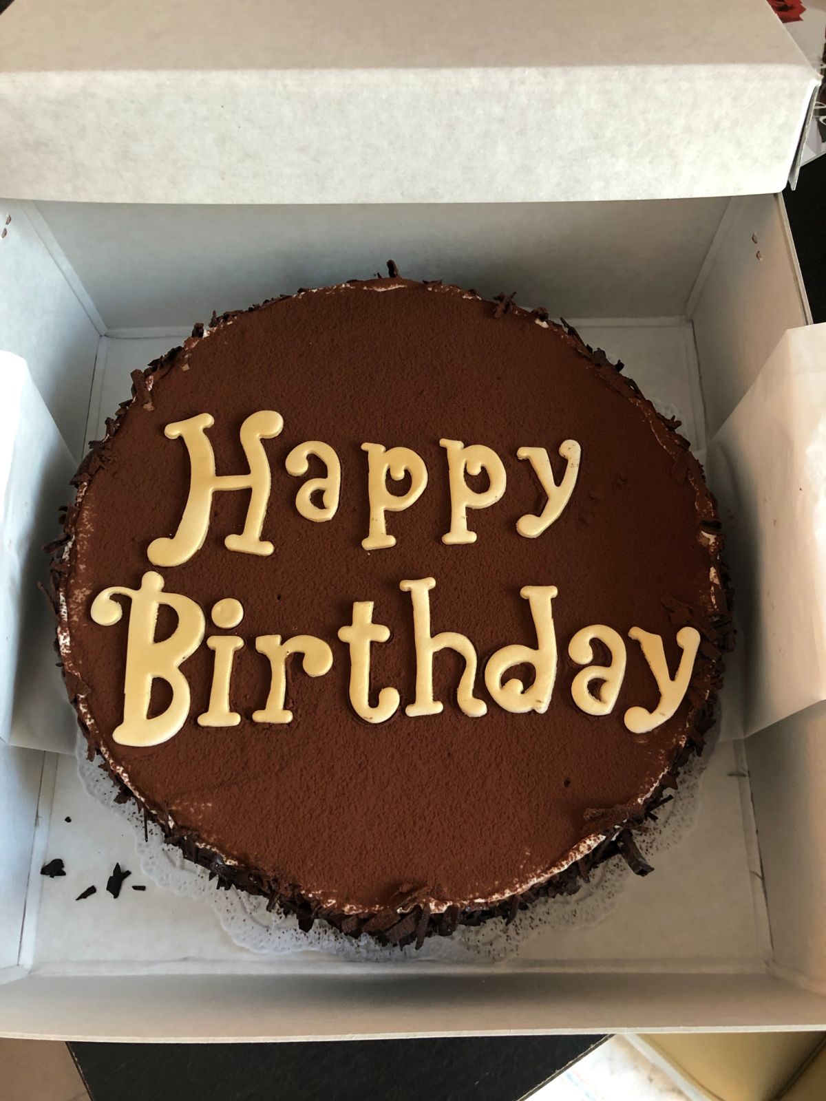Round dark chocolate cake with yellow fondant lettering