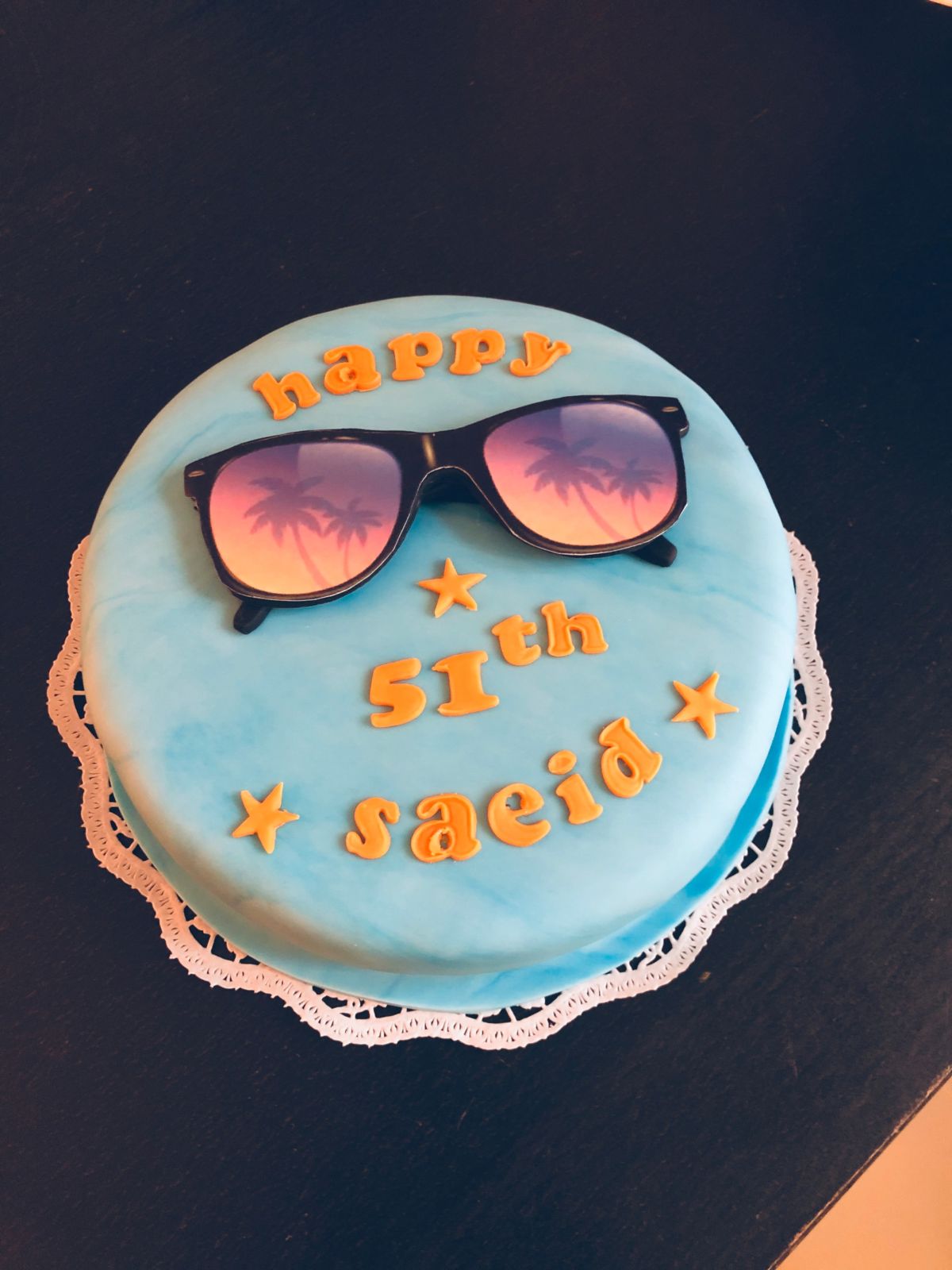 50th birthday cake with light blue fondant, fondant sunglasses with sunset scene, and stars