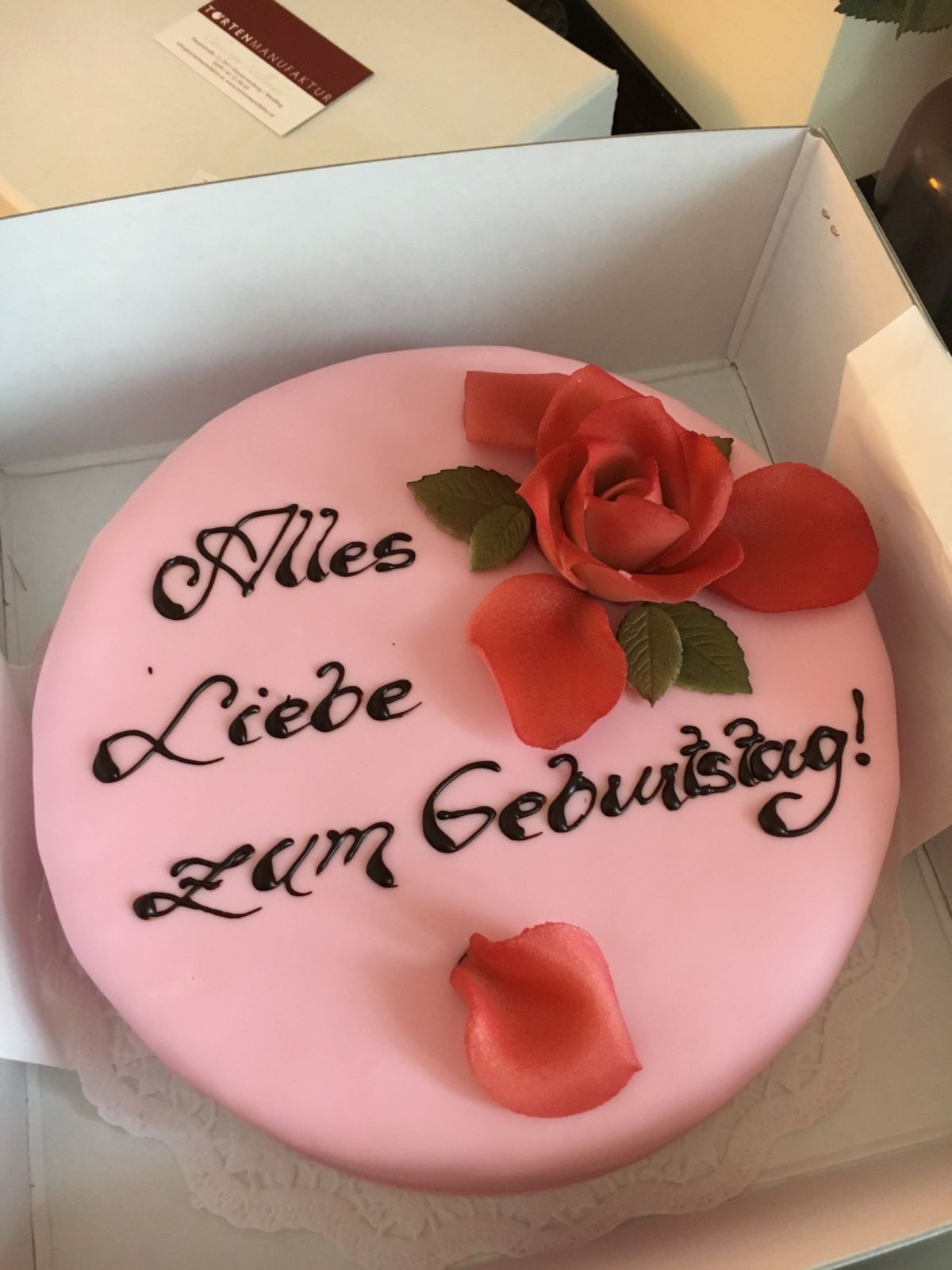 Pink round birthday cake decorated with red fondant roses