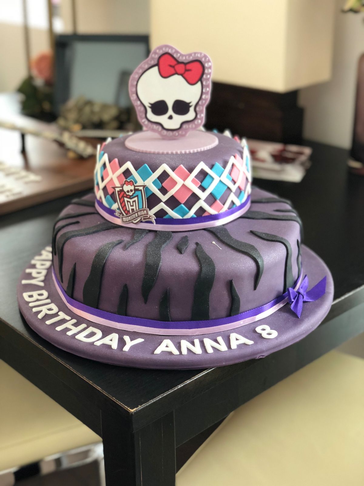 Two-tier Monster High cake in purple with zebra stripes, a harlequin pattern and a skull topper