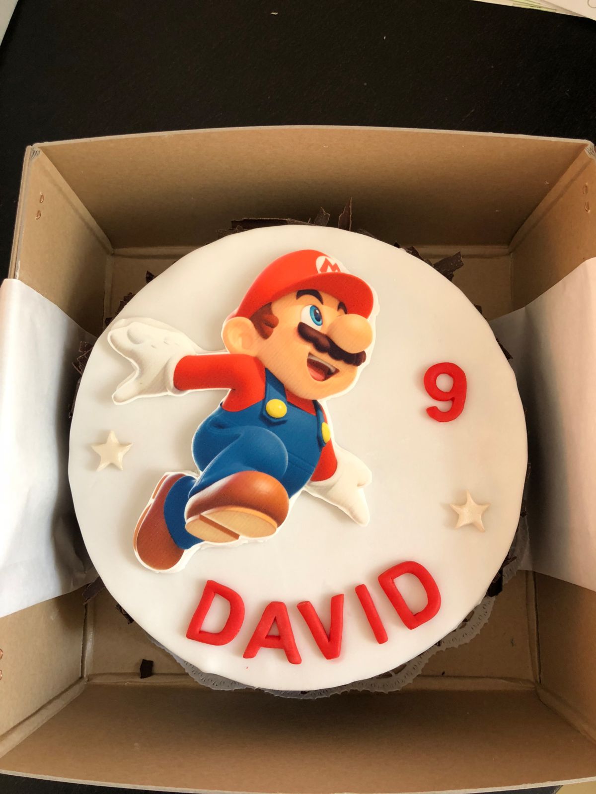 Children’s birthday cake with Super Mario character figure, white fondant, number 9, and star decorations