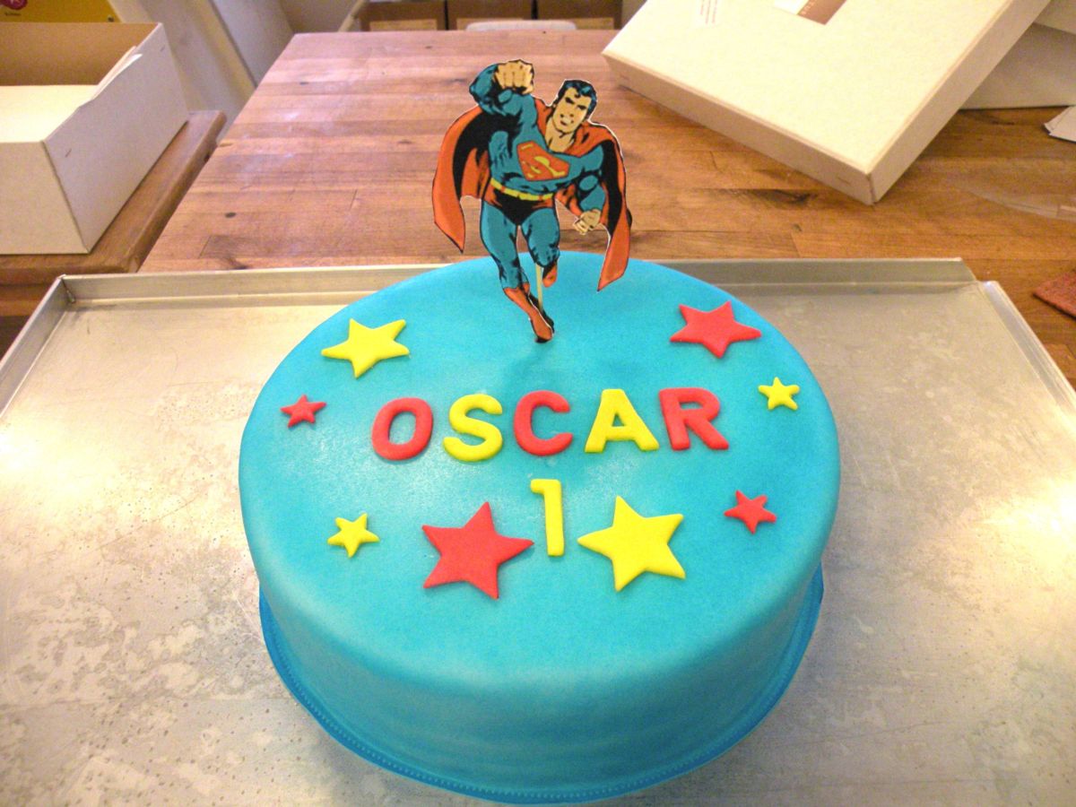 Turquoise children’s birthday cake with Superman figure and red and yellow stars