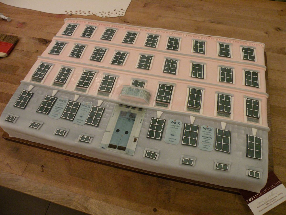 Pink townhouse facade cake with dozens of detailed fondant windows and doors