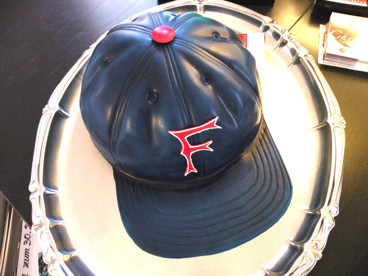 Navy baseball cap cake with red emblem and top button detail