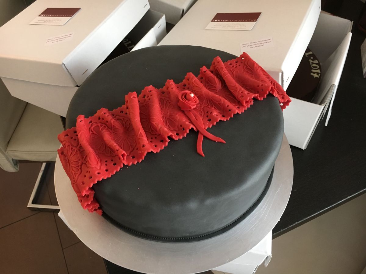Two-tier cake with dark fondant and red ruffled texture accent