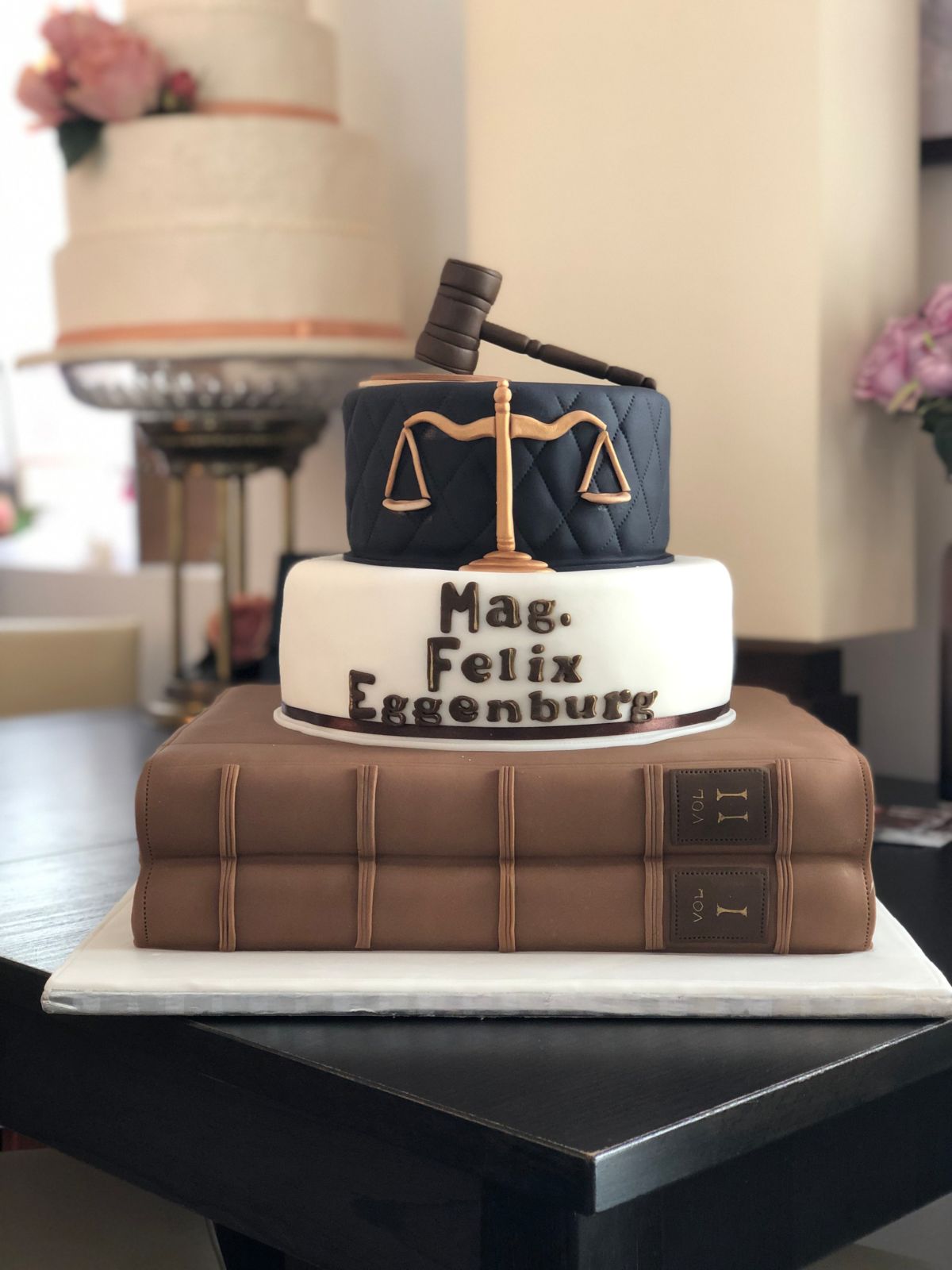 Three-tier lawyer cake featuring law book base, scales of justice, and judge’s gavel