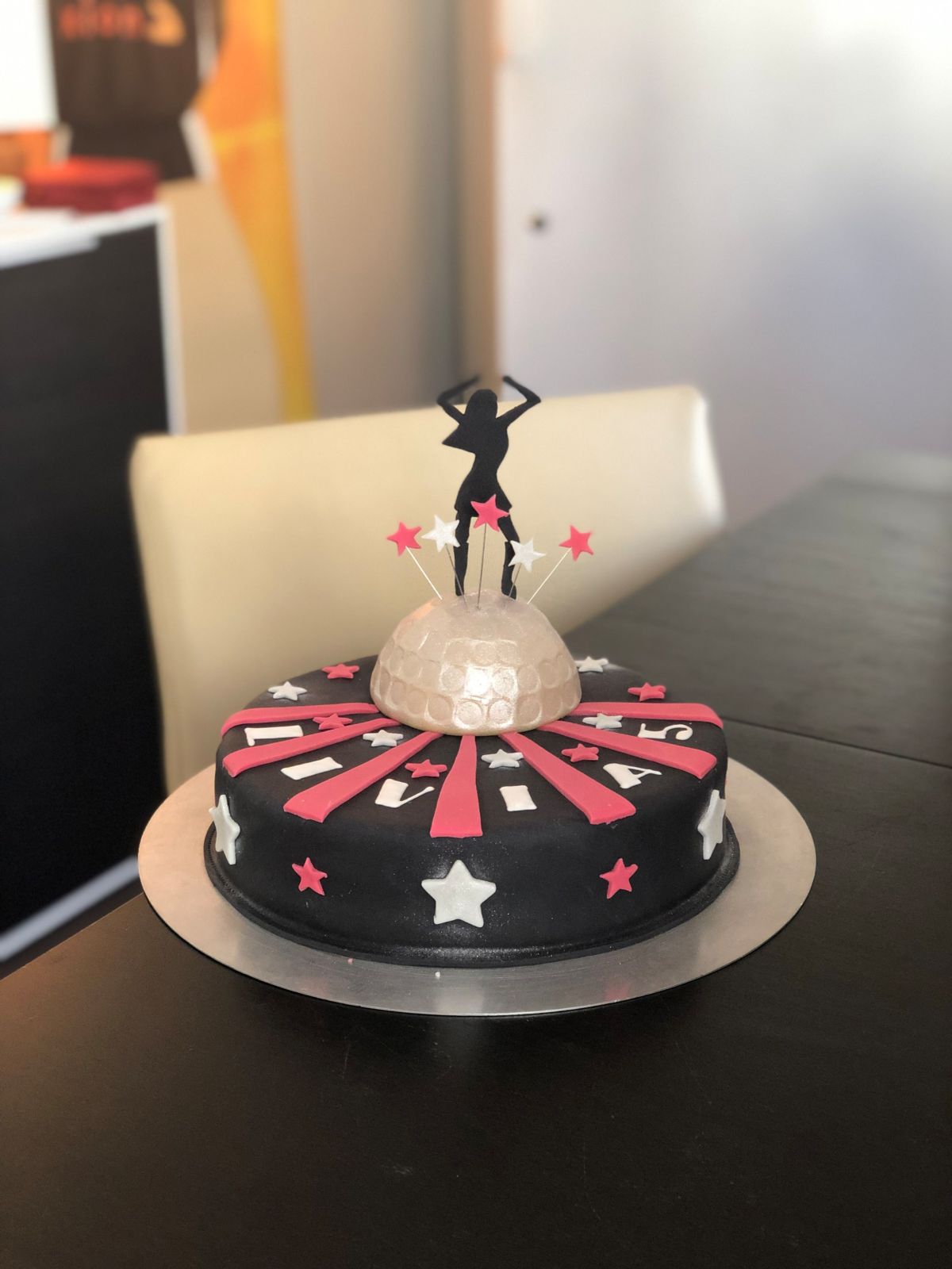 Stage-themed cake in black fondant with stars and a performer figure