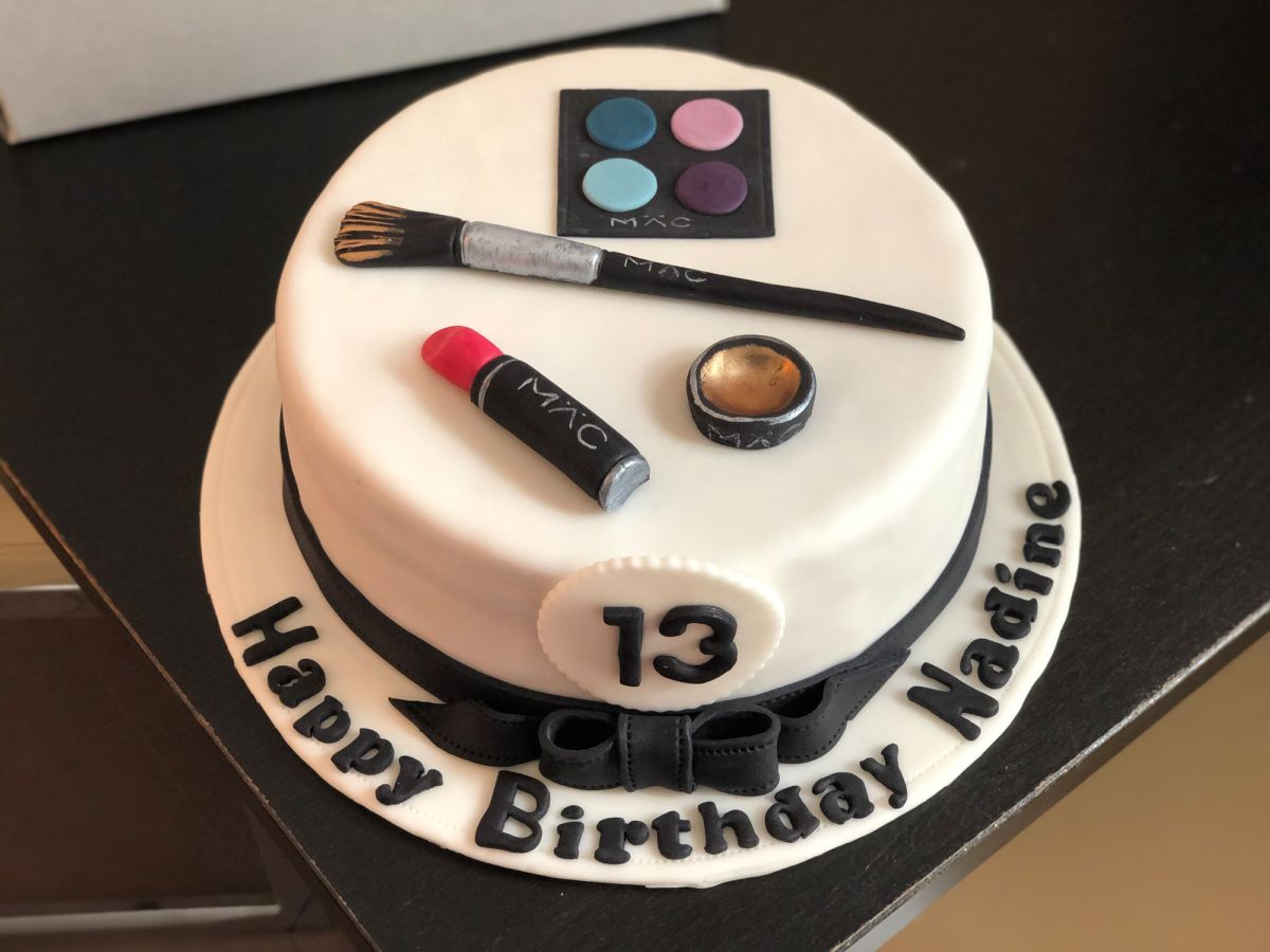 13th birthday cake decorated with eyeshadow palette, makeup brush, and lipstick