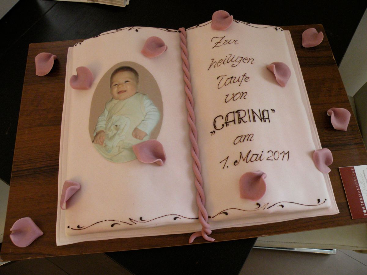 Christening cake shaped like an open book with baby photo and rose petals